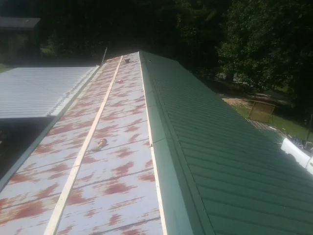 Old rusted panels beside newly installed green metal roofing — Wind Damage Roof Repair by Roofing Brothers in Kanawha