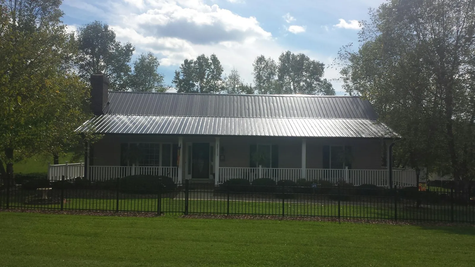 Gray metal roof on a brick ranch with a full width front porch — Gutter Guard Installation work by our crew in Kanawha