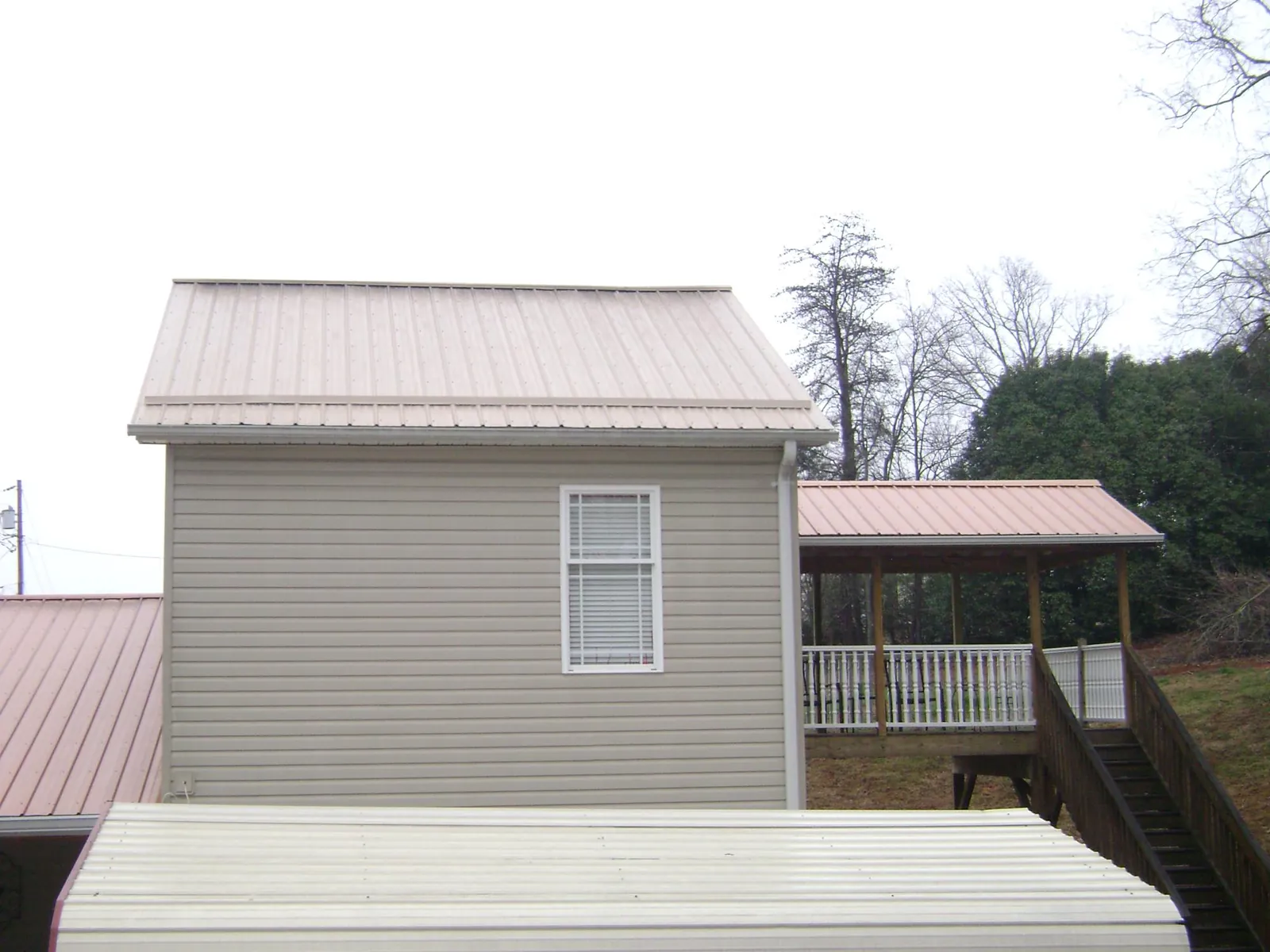 Tan metal roofs on a two story addition and attached porch, from a Roof Replacement job in Kanawha