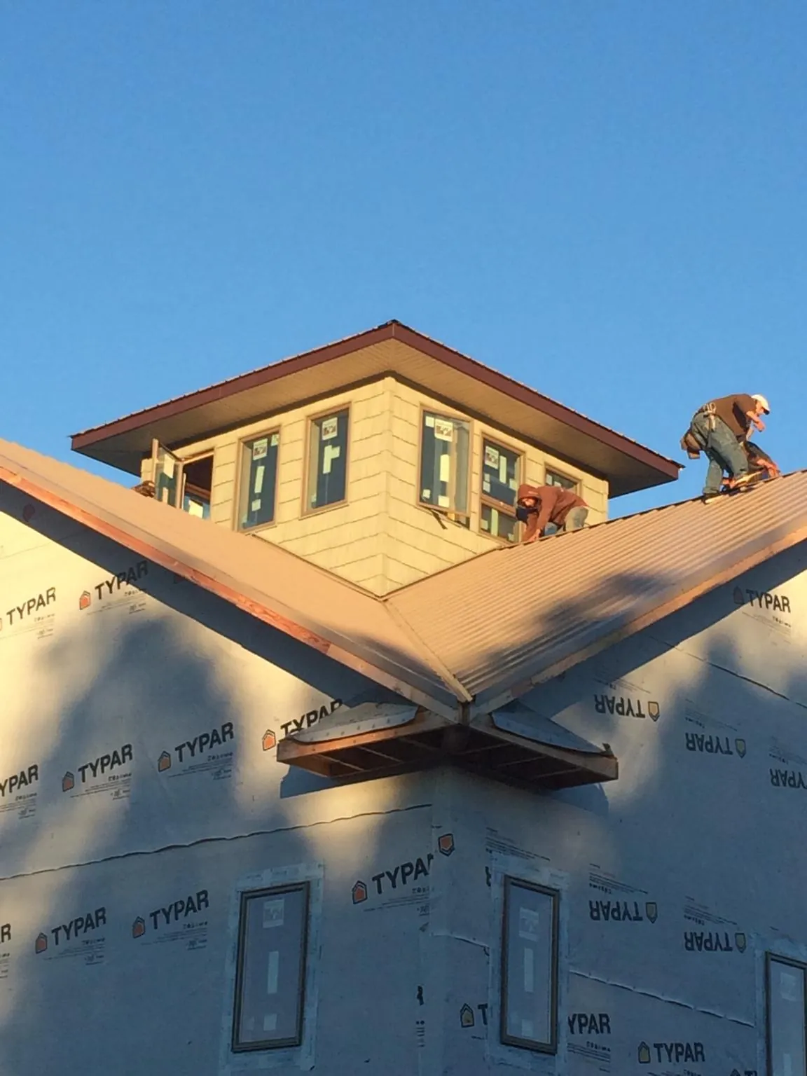 Roofers working around a rooftop cupola on a new metal roof at sunset — Roof Waterproofing in Kanawha by Roofing Brothers